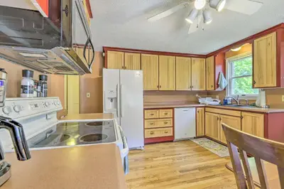 a kitchen with a white refrigerator and wooden cabinets at Granby Getaway in the Woods with Spacious Yard! in Granby