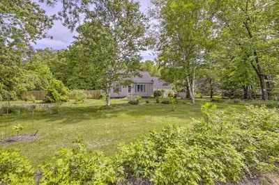 a white house with a yard with trees at Granby Getaway in the Woods with Spacious Yard! in Granby
