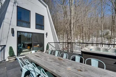a deck with a wooden table and chairs and a tub at Wilmington Chalet with Hot Tub Less Than 8 Mi to Mount Snow! in Wilmington