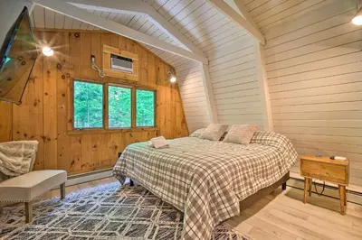 a bedroom with a bed in a room with wooden walls at Wilmington Chalet with Hot Tub Less Than 8 Mi to Mount Snow! in Wilmington