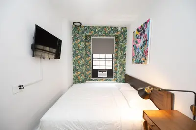 a small bedroom with a bed and a tv at The Flat NYC in New York