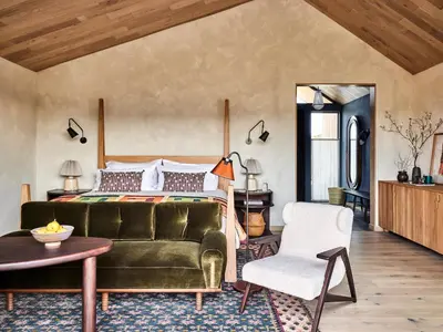 a bedroom with a green couch and a bed at Wildflower Farms, Auberge Collection in Gardiner