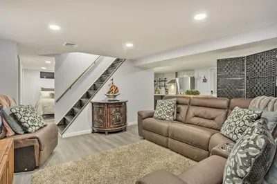a living room with a couch and a staircase at Saddle Brook Studio with Patio - Near NYC! in Saddle Brook