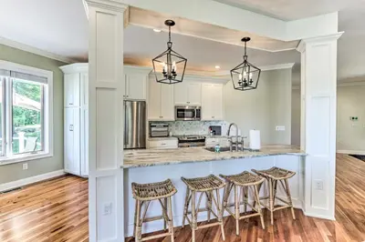 a kitchen with a island with bar stools at Elegant Middlefield Getaway with Game Room! in Middlefield