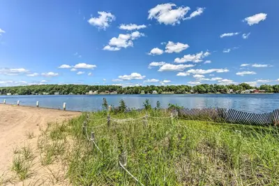 a fence on a beach next to a body of water at Elegant Middlefield Getaway with Game Room! in Middlefield