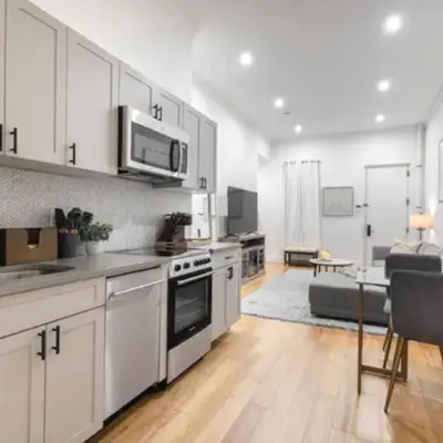 a kitchen with white cabinets and a living room at Modern Holiday Apartment with Strategic Location in New York in New York