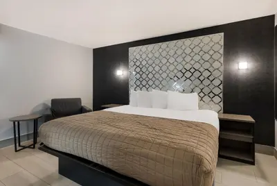 a bedroom with a large bed and a chair at Essence Express Wayne in Wayne