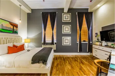 a bedroom with a large bed and two windows at Henry Norman Hotel in Brooklyn