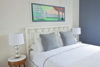 a bedroom with a white bed with two lamps and a painting at Henry Norman Hotel in Brooklyn