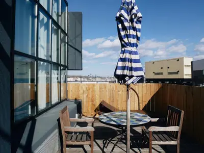 a table and chairs on a balcony with an umbrella at Henry Norman Hotel in Brooklyn