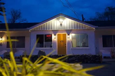 a white house with a yellow door at night at Cobmin Ridge Motel in Branchville