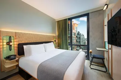 a hotel room with a bed and a large window at Moxy Brooklyn Williamsburg in Brooklyn