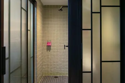 a bathroom with a shower with a glass door at Moxy Brooklyn Williamsburg in Brooklyn