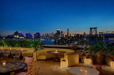 a rooftop patio with tables and chairs and a view of the city at Moxy Brooklyn Williamsburg in Brooklyn