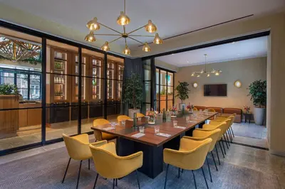 a large dining room with a long table and yellow chairs at Moxy Brooklyn Williamsburg in Brooklyn