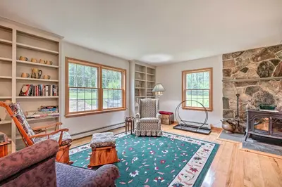 a living room with a fireplace and a stone wall at Wilmington Home on 18 Acres about 9 Mi to Skiing! in Wilmington