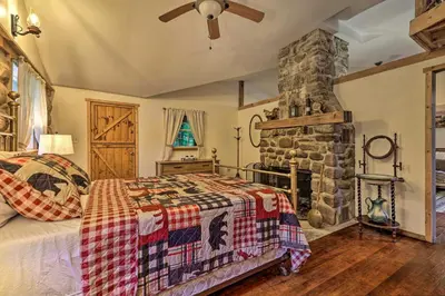 a bedroom with a bed and a stone fireplace at Cabin with Trails and Creek! 23 Mi to Camelback Slopes in Greentown