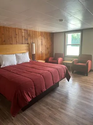 a bedroom with a red bed and two chairs at Starlight Inn in Bennington