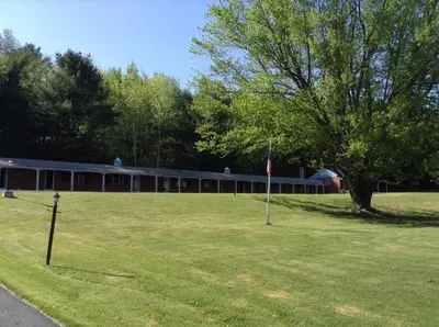 a building with a tree and a flag in the grass at Starlight Inn in Bennington