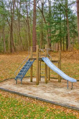 a playground with a slide in a park at The Ponds at Foxhollow in Lenox