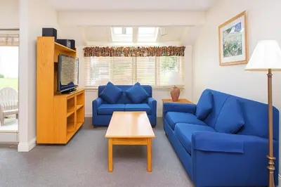 a living room with two blue couches and a table at The Ponds at Foxhollow in Lenox