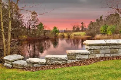 a stone bridge over a pond at sunset at The Ponds at Foxhollow in Lenox
