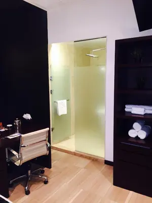 a bathroom with a shower and a desk and a chair at The One Boutique Hotel in Queens