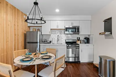 a kitchen with white cabinets and a table with chairs at Ski In Ski Out Cabin on Hunter Mtn Seasonal Pool Access w Panoramic Views Hike Swim Fish Relax in Lanesville