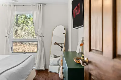 a bedroom with a bed and a mirror next to a window at Ski In Ski Out Cabin on Hunter Mtn Seasonal Pool Access w Panoramic Views Hike Swim Fish Relax in Lanesville