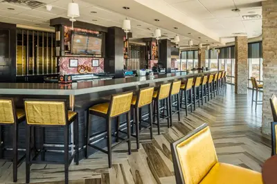 a bar in a restaurant with yellow bar stools at Crowne Plaza Saddle Brook by IHG in Saddle Brook