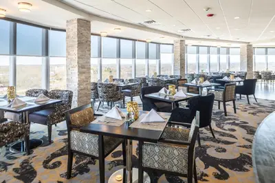 a dining room with tables and chairs and windows at Crowne Plaza Saddle Brook by IHG in Saddle Brook