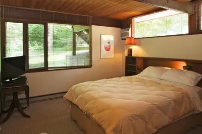 a bedroom with a bed and a desk and windows at The Cottage in Stockbridge