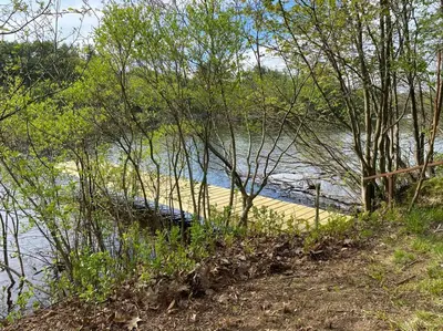 a wooden dock in the middle of a body of water at Adirondack Waterfront Cabin Upper Hudson Tributary in Lake Luzerne