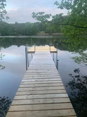 a wooden dock in the middle of a lake at Adirondack Waterfront Cabin Upper Hudson Tributary in Lake Luzerne