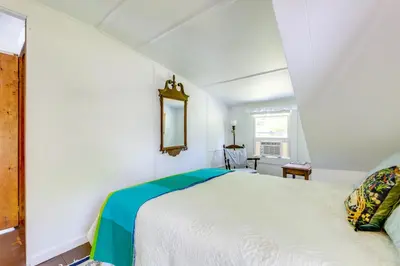 a bedroom with a white bed and a mirror at Lakefront Cottage with Covered Porch and Dock! in Coventry