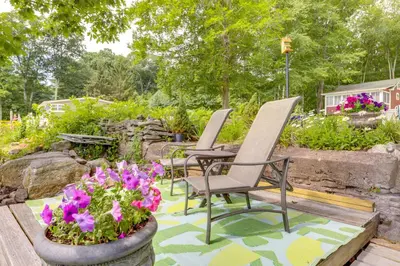 two chairs and a table and flowers in a garden at Lakefront Cottage with Covered Porch and Dock! in Coventry