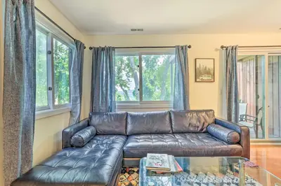 a leather couch in a living room with windows at Sun-Lit Vernon Condo Less Than 2 Mi to Ski Resort! in Vernon Township