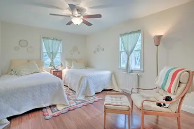 a bedroom with two beds and a chair with a dog sitting in a chair at Ashley Falls Home with Fire Pit Hike and Ski! in Ashley Falls