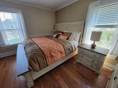 a bedroom with a bed and a dresser and two windows at The Hidden Inn in South Kortright