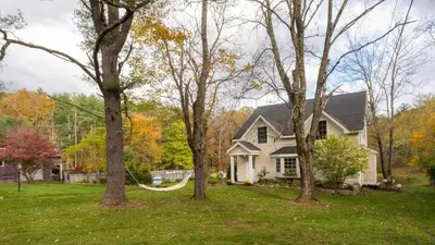 a house with a hammock in the yard at 4BDR Heritage Estate w Pool Private Pond Fire Pit Cortland by AvantStay in Saugerties