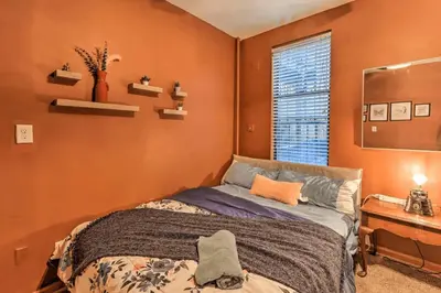 a bedroom with orange walls and a bed and a window at 1850s historic Row House 7min train to NYC with private backyard in Jersey City