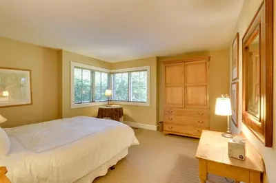 a bedroom with a bed and a table and windows at Stunning Warren Lakefront Home Deck, Grill, Sauna in Warren