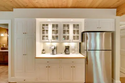 a kitchen with white cabinets and a refrigerator at Stunning Warren Lakefront Home Deck, Grill, Sauna in Warren