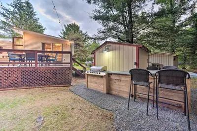 a small cabin with a grill and chairs in a yard at Glamping Getaway in Woodstock Lake Campground in East Berne