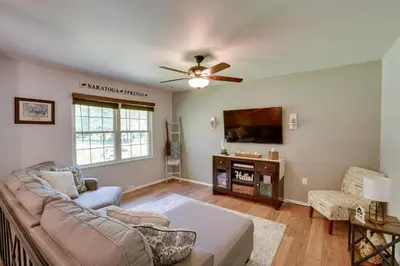 a living room with a couch and a flat screen tv at Saratoga Springs Haven with Pool and Fire Pit! in Saratoga Springs