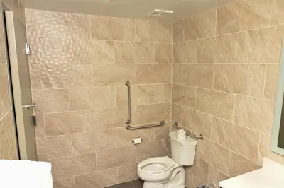 a bathroom with a toilet and a tiled wall at Days Inn by Wyndham Bronx NYC in Bronx