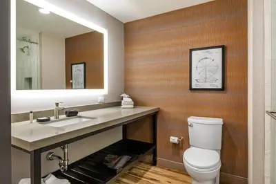 a bathroom with a toilet and a sink and a mirror at Cambria Hotel New Haven University Area in New Haven