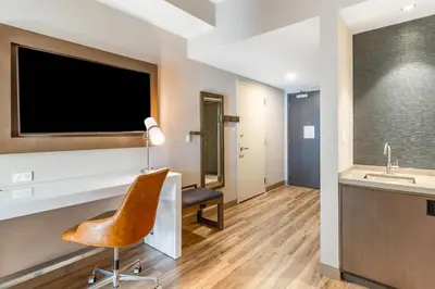 a bathroom with a television and a chair at Cambria Hotel New Haven University Area in New Haven