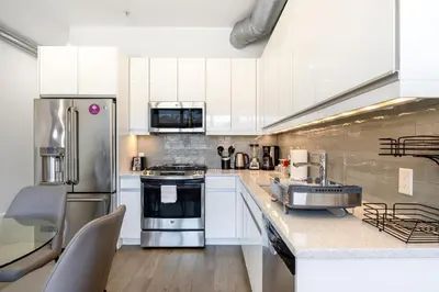 a kitchen with white cabinets and stainless steel appliances at Dharma Home Suites Hoboken in Hoboken