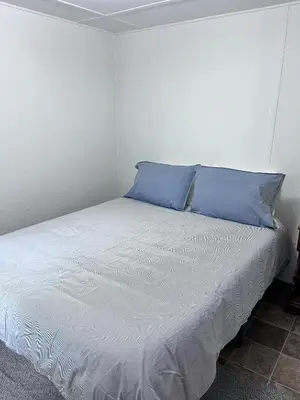 a white bed with blue pillows in a room at Camp Hudson Pines in Corinth